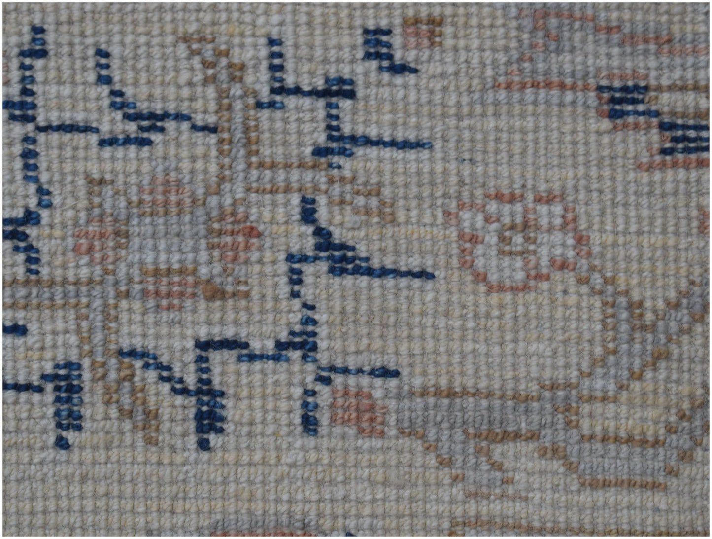 A close-up of a handmade Afghan Chobi rug featuring geometric blue patterns on a cream wool base.
