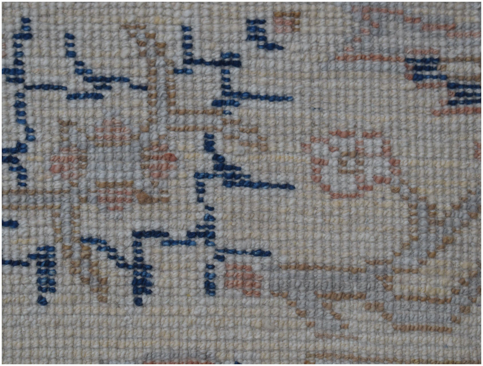 A close-up of a handmade Afghan Chobi rug featuring geometric blue patterns on a cream wool base.