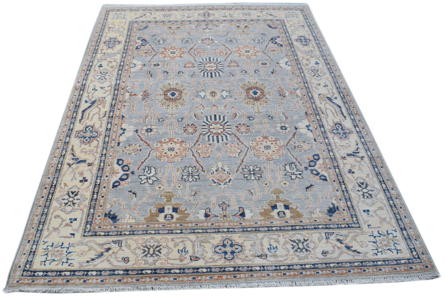 A handmade Afghan Chobi rug featuring a traditional floral pattern in soft blue and beige tones.