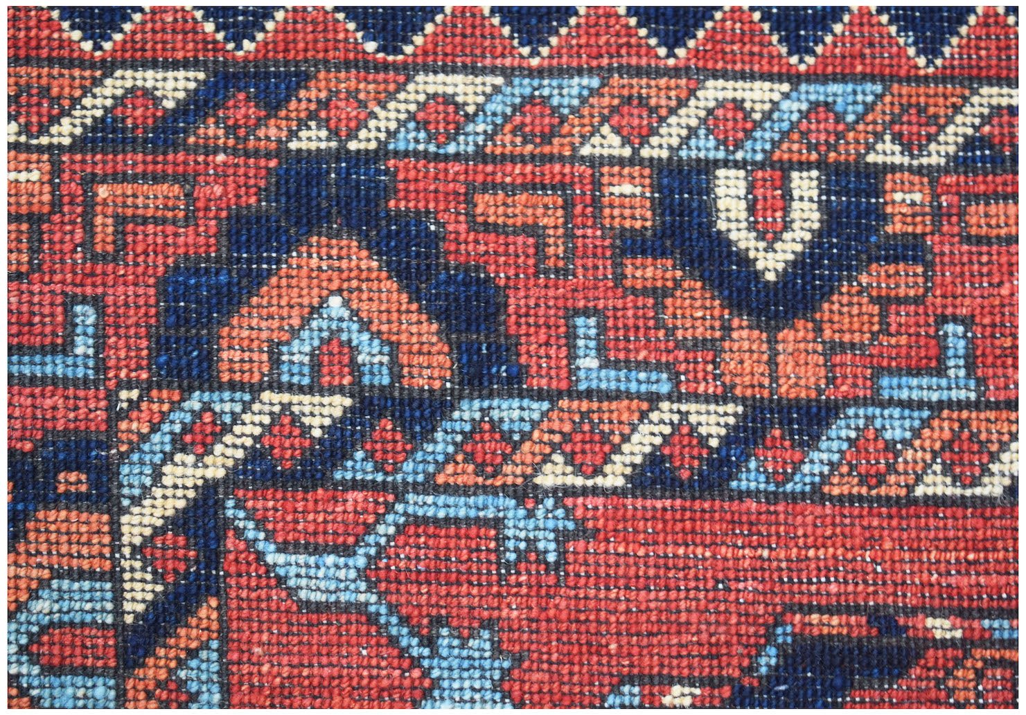 A close-up of a handwoven Afghan Chobi rug featuring intricate geometric patterns in red and blue.