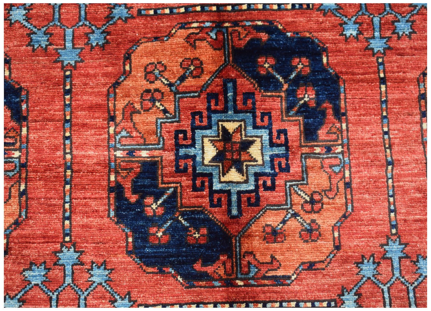 Handwoven Afghan Chobi rug featuring a geometric central medallion in red, blue, and orange tones.