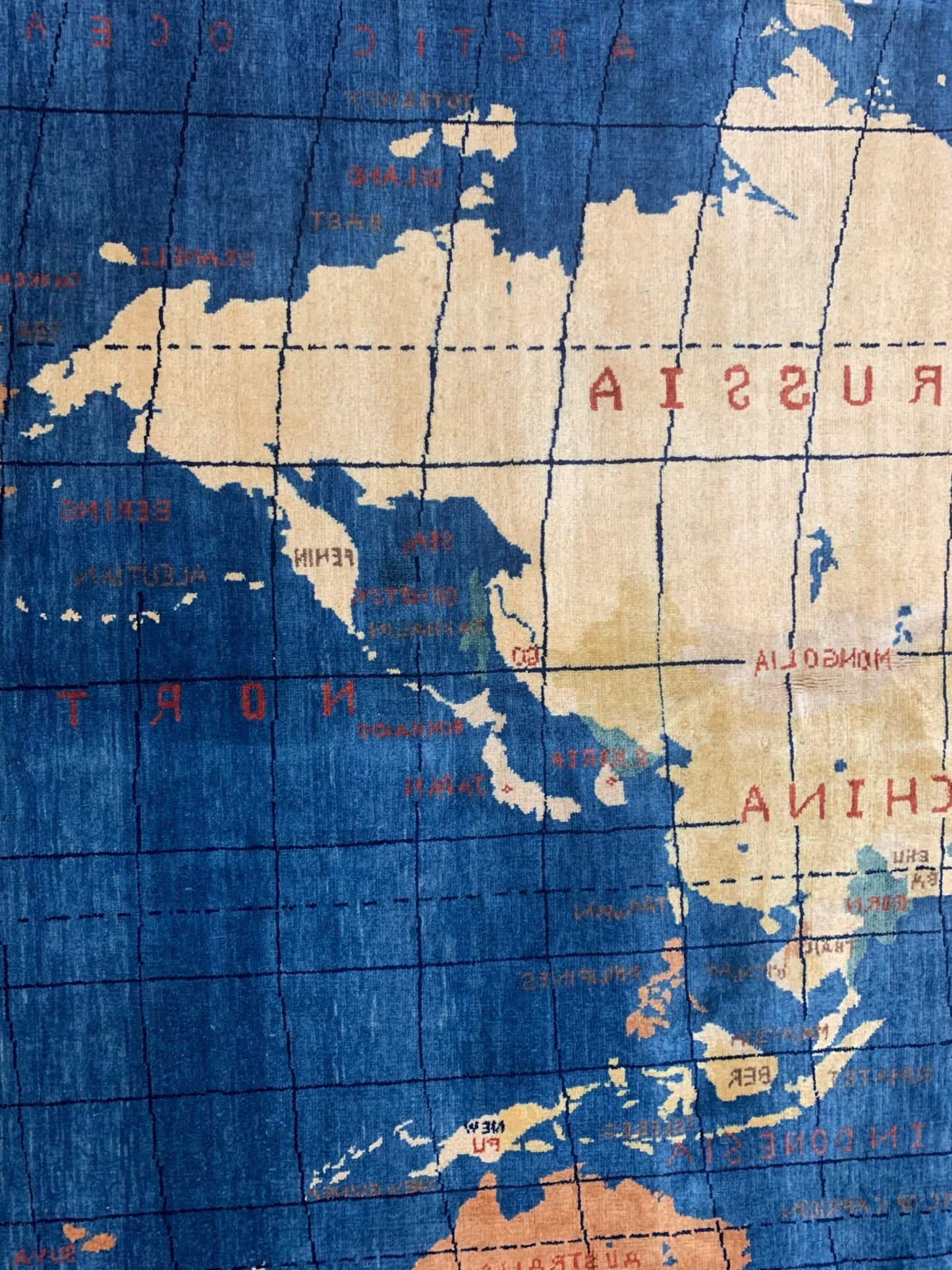 A handmade Afghan Chobi rug featuring a stylized world map design in blue and neutral tones.
