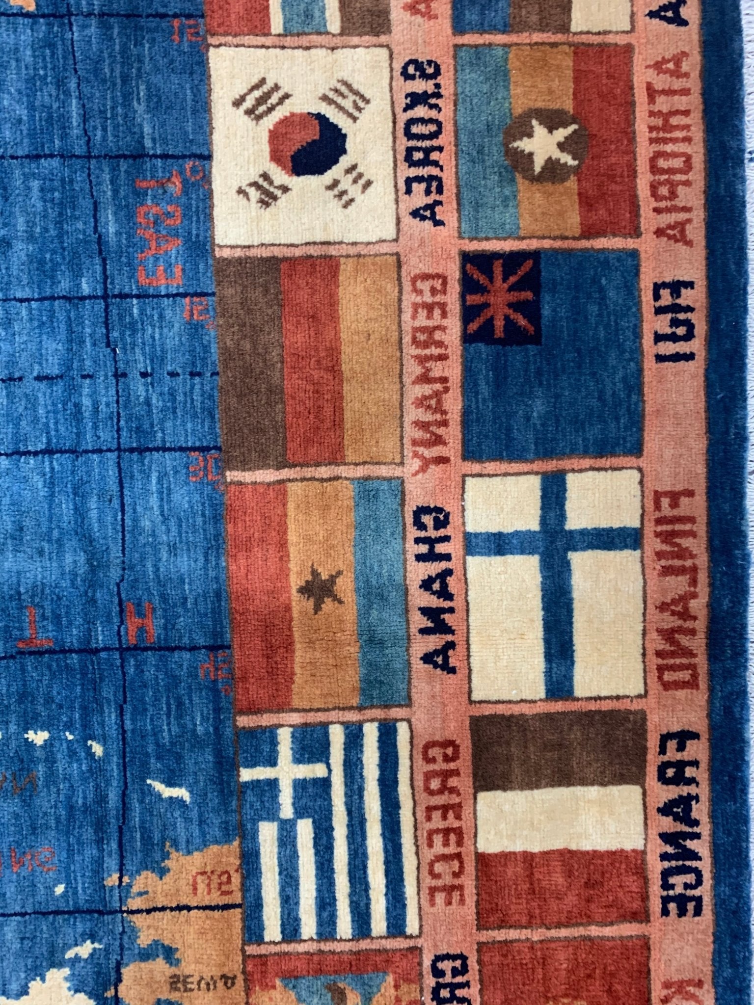 Handmade Afghan Chobi rug featuring a blue map border with various national flags and text.