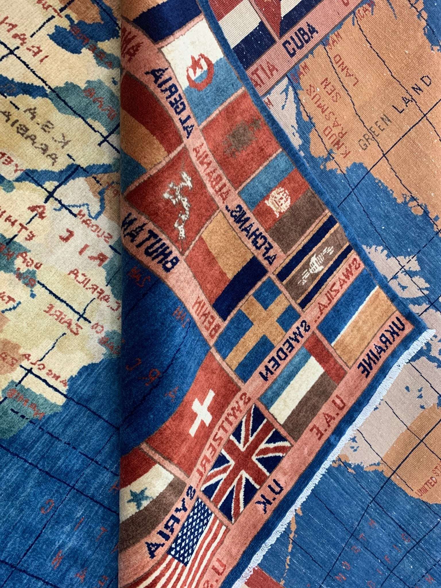 A handmade Afghan Chobi rug featuring a world map design with various national flags.