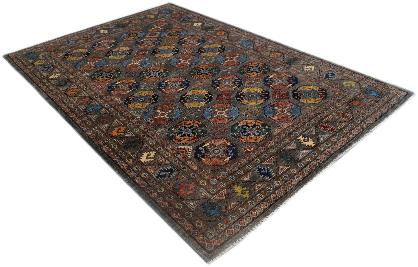 A handmade Afghan Chobi rug featuring a repeating geometric pattern in earthy tones on a grey field.