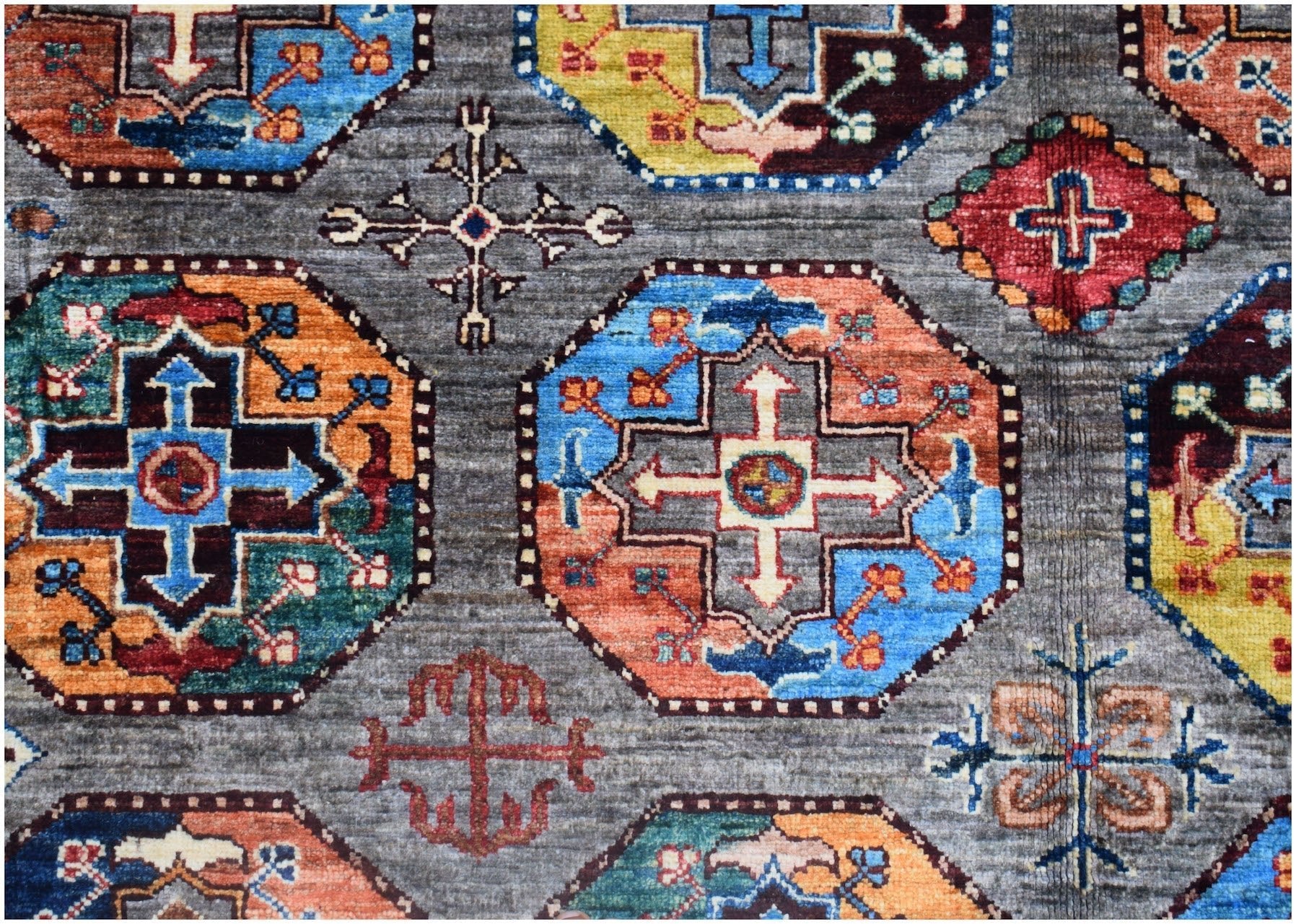 Handmade Afghan Chobi rug featuring a geometric pattern of colorful octagons on a gray background.