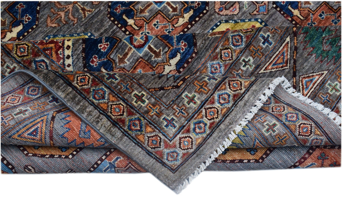 A handmade Afghan Chobi rug featuring a grey field with intricate geometric patterns and fringe.