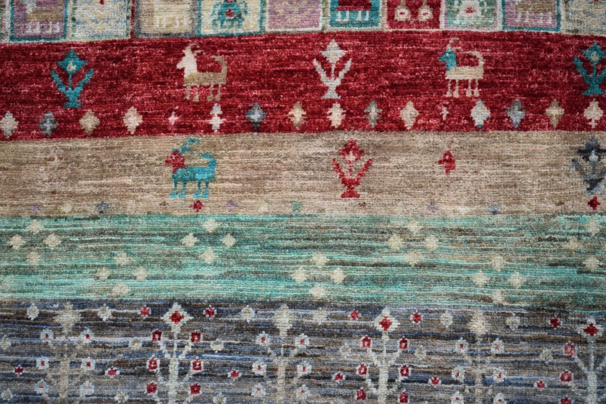 Handmade Afghan Chobi rug featuring horizontal bands of geometric patterns and animal motifs.