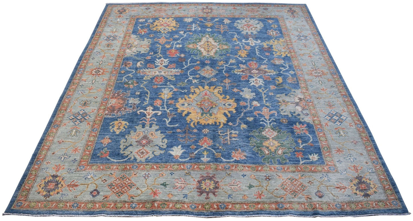A handmade Afghan Chobi rug featuring a traditional floral pattern in blue and earthy tones.