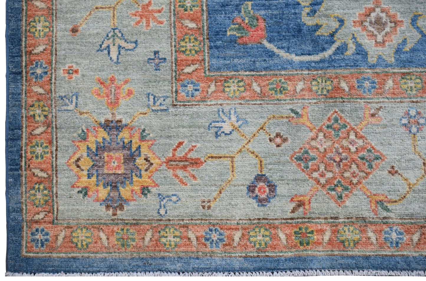 Handmade Afghan Chobi rug featuring a light blue field with intricate floral and geometric motifs.