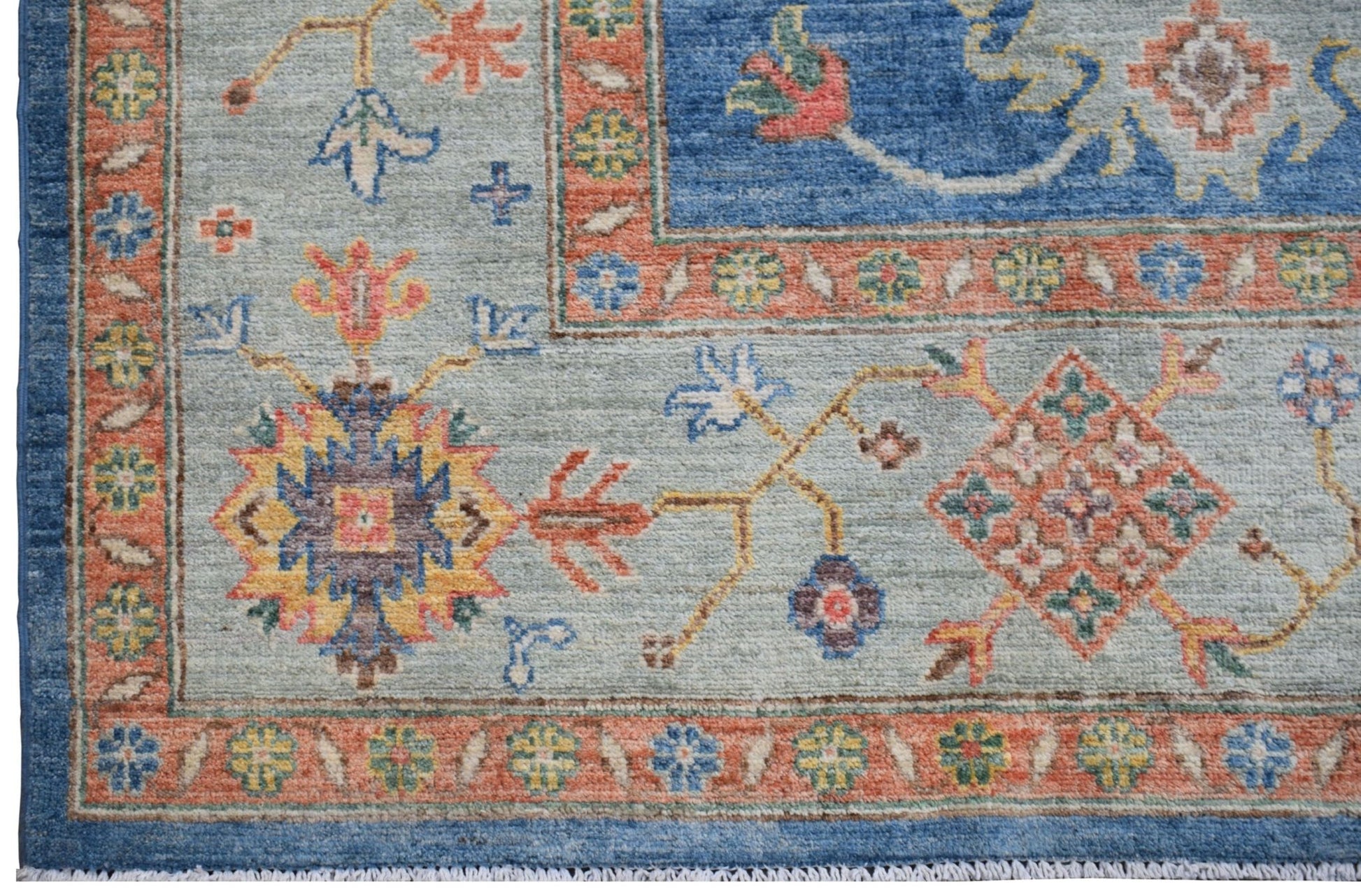 Handmade Afghan Chobi rug featuring a light blue field with intricate floral and geometric motifs.