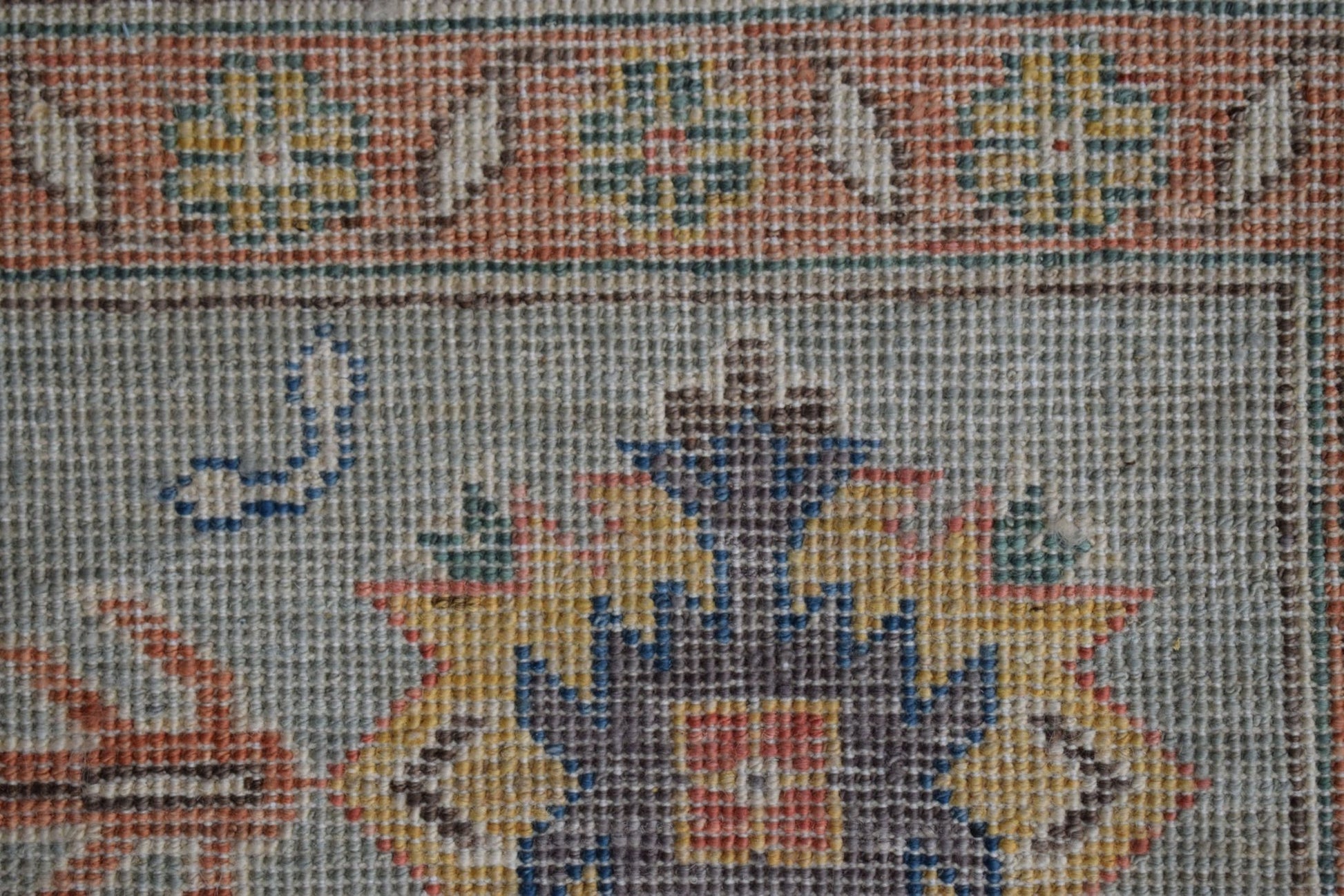 A close-up of a handmade Afghan Chobi rug featuring intricate floral patterns in earthy tones.