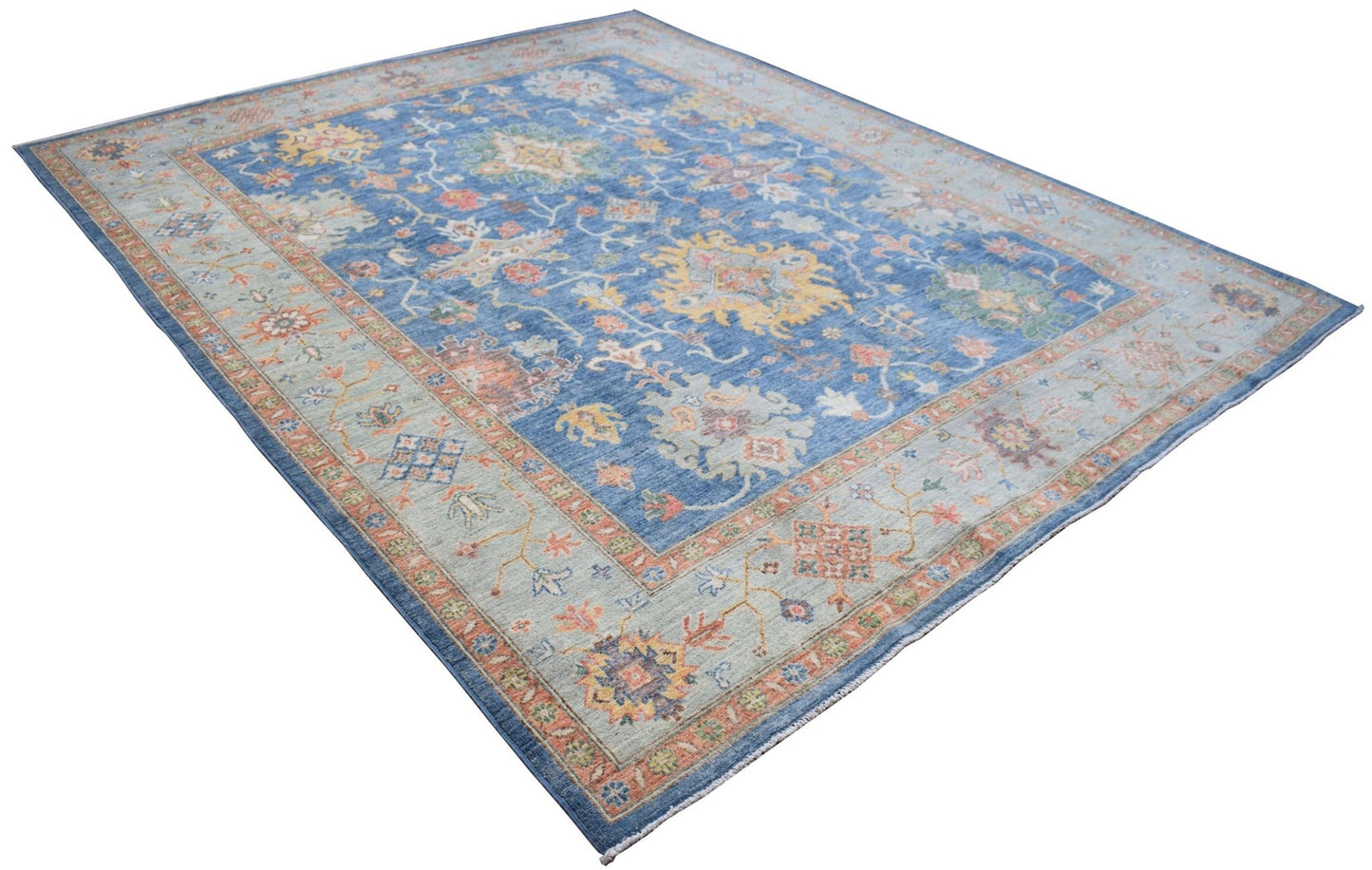 A handmade Afghan Chobi rug featuring a traditional floral pattern in blue, beige, and orange tones.