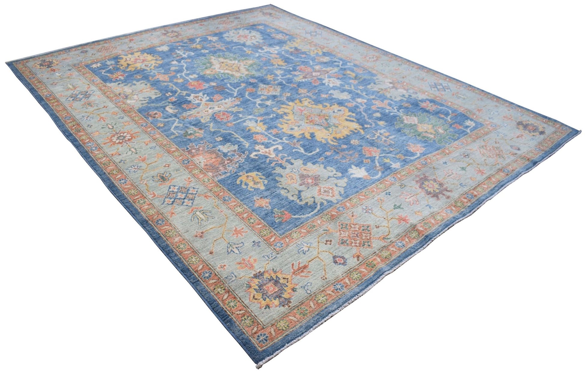 A handmade Afghan Chobi rug featuring a traditional floral pattern in blue, beige, and orange tones.