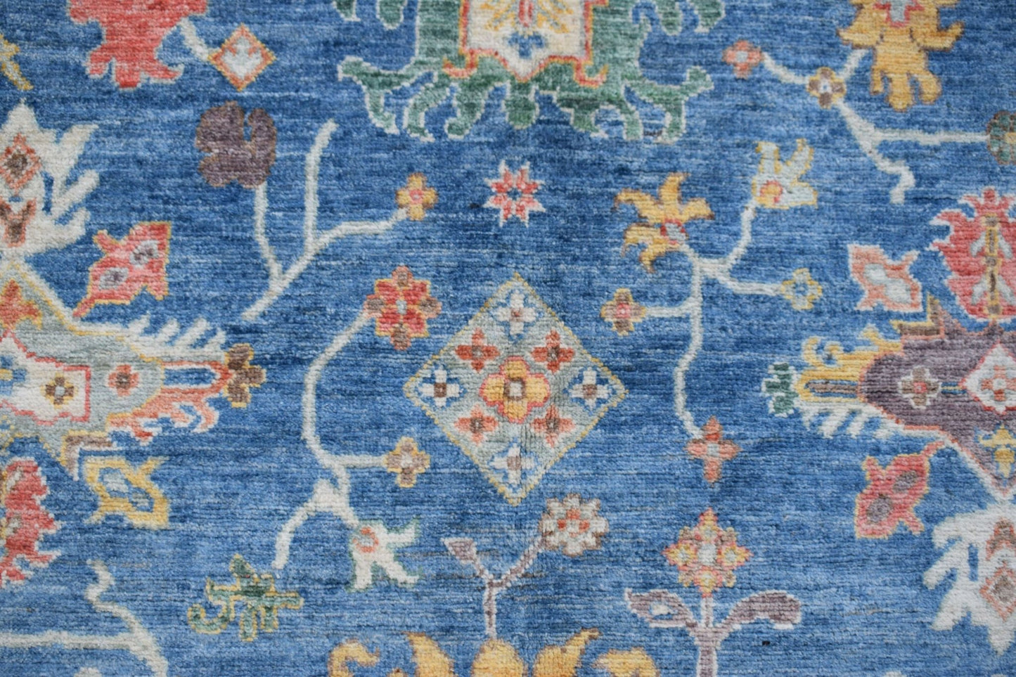 Handmade Afghan Chobi rug featuring a traditional floral pattern on a blue wool background.