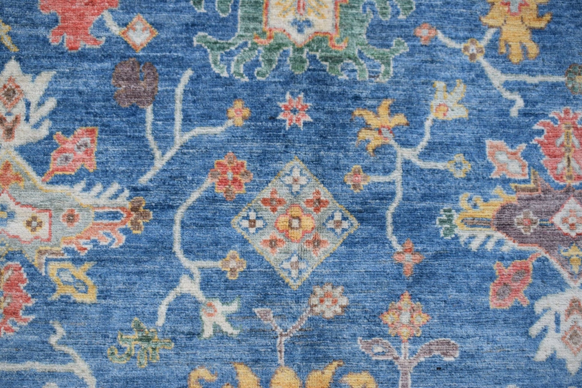 Handmade Afghan Chobi rug featuring a traditional floral pattern on a blue wool background.