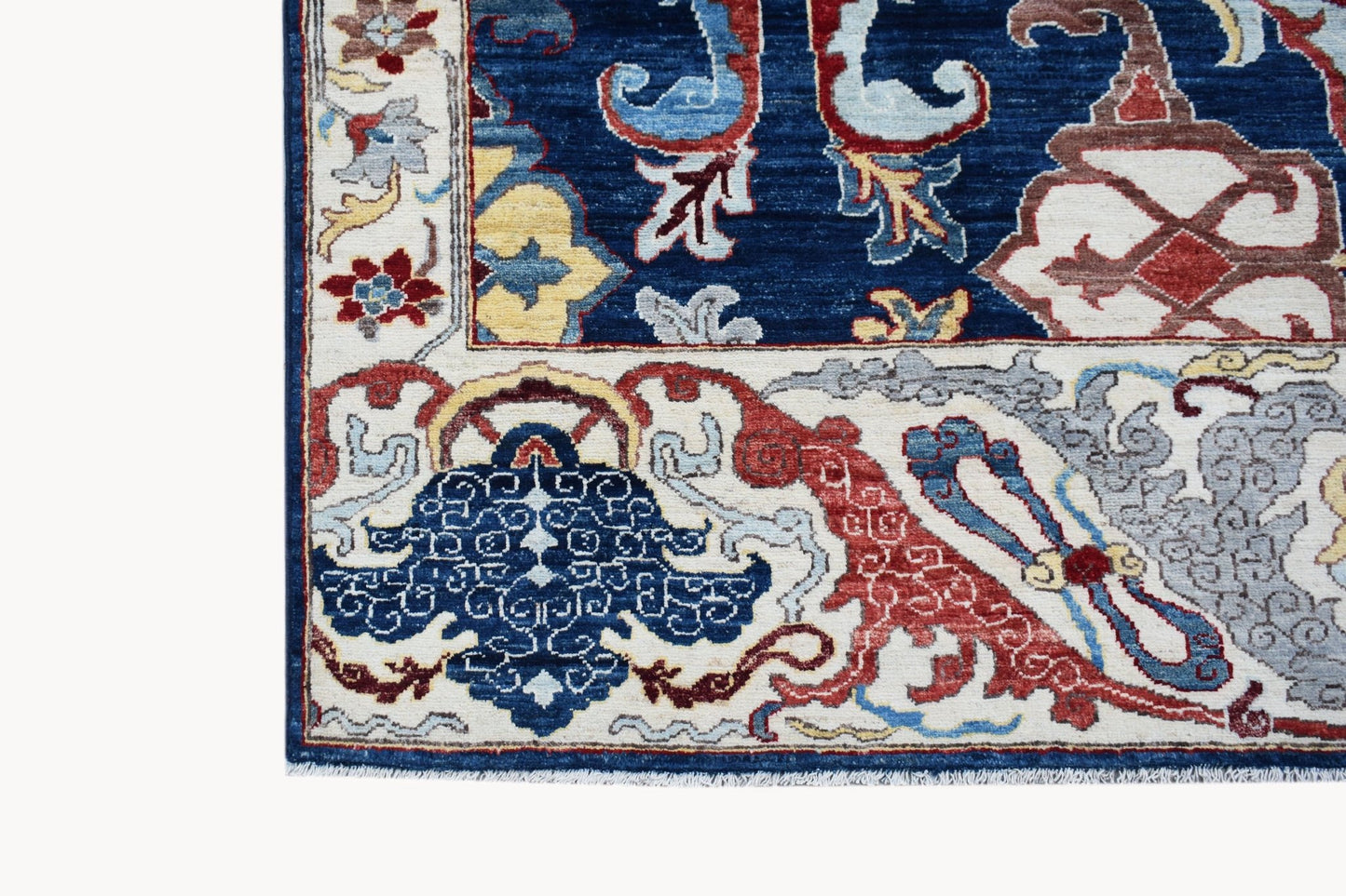 A corner detail of a handwoven Afghan Chobi rug featuring intricate floral patterns in blue and red.