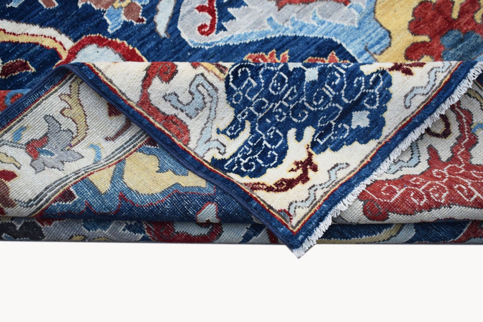 A folded Afghan Chobi rug featuring a traditional Bidjar pattern in blue, red, and cream tones.