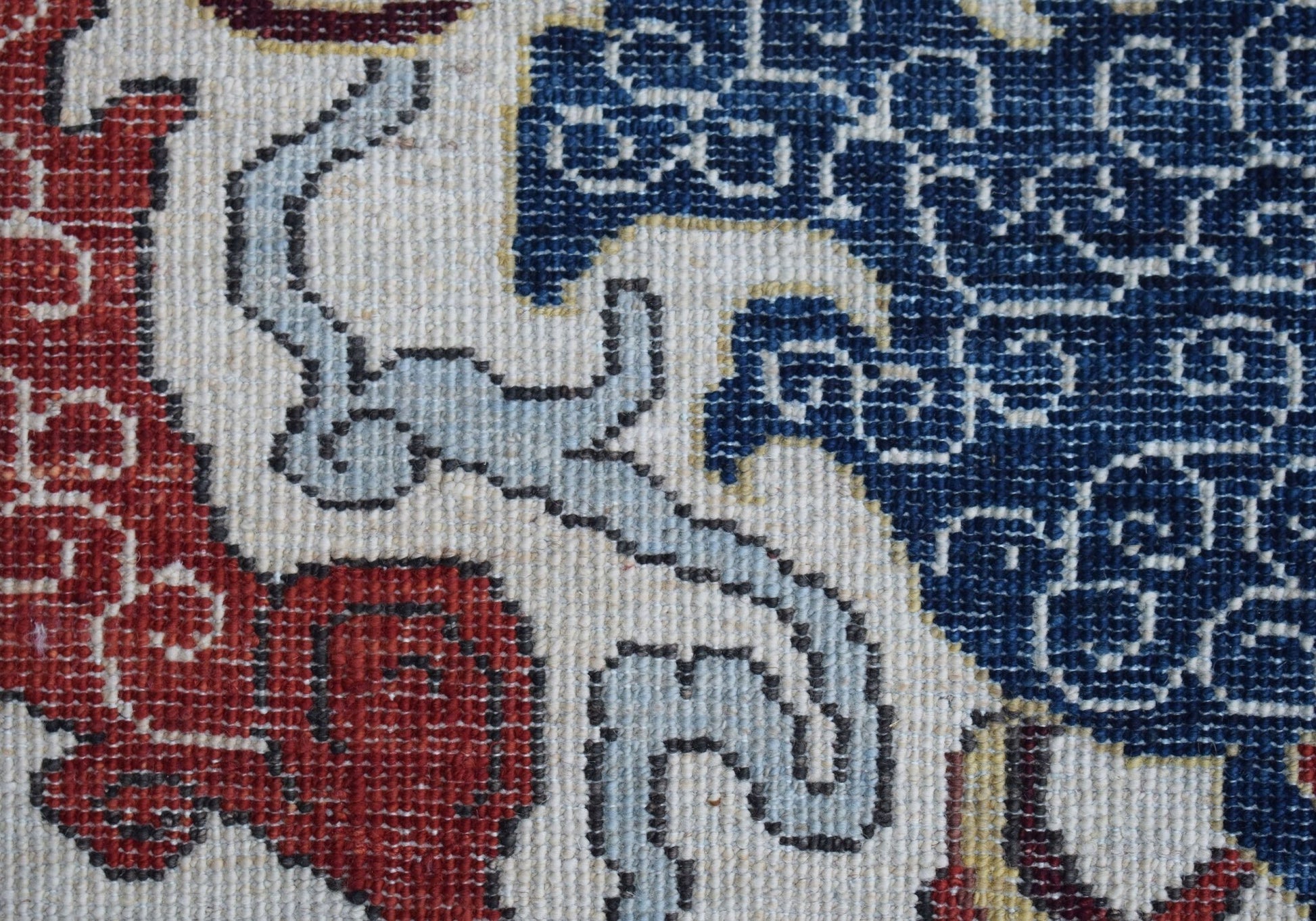 A close-up of a handwoven Afghan Chobi rug featuring intricate blue, red, and cream patterns.