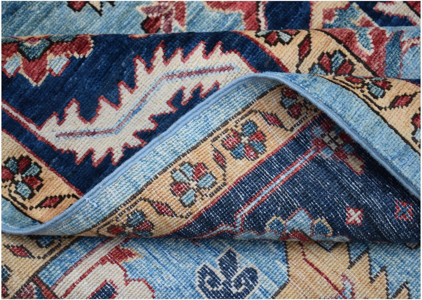 A folded Afghan Chobi rug featuring traditional floral patterns in blue, red, and beige tones.
