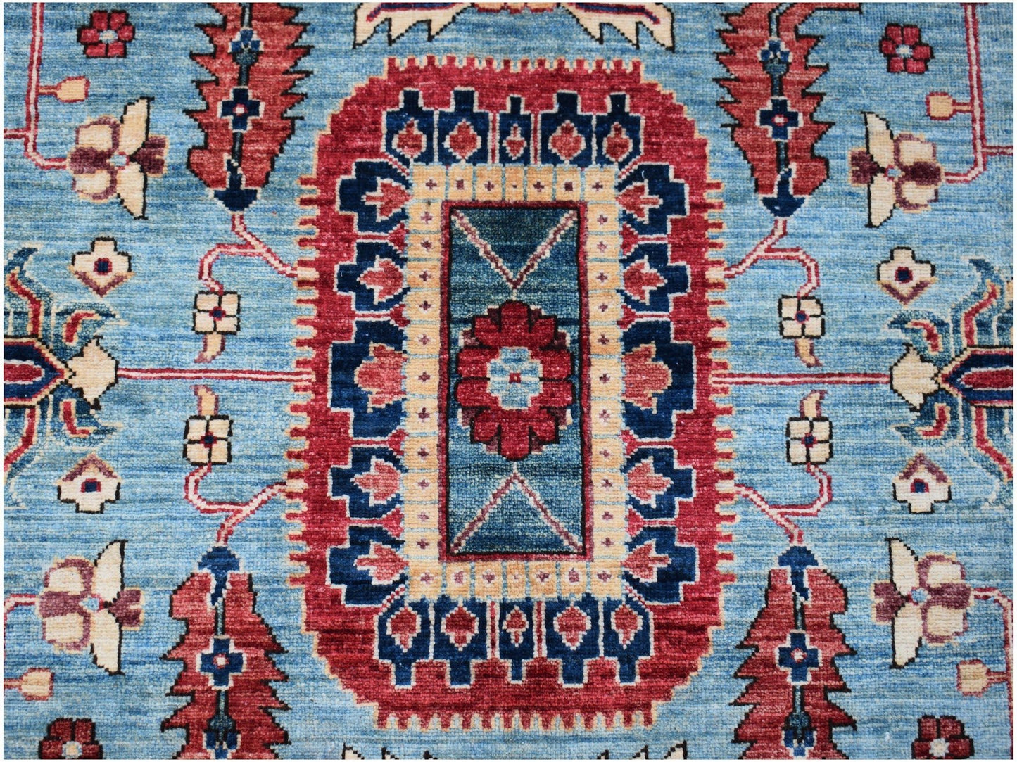 An Afghan Chobi rug featuring a central floral medallion on a blue field with red geometric borders.