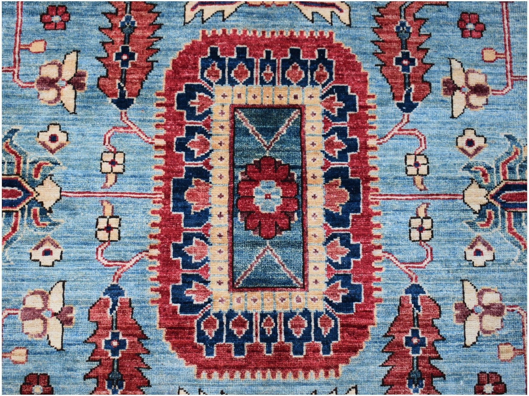 An Afghan Chobi rug featuring a central floral medallion on a blue field with red geometric borders.