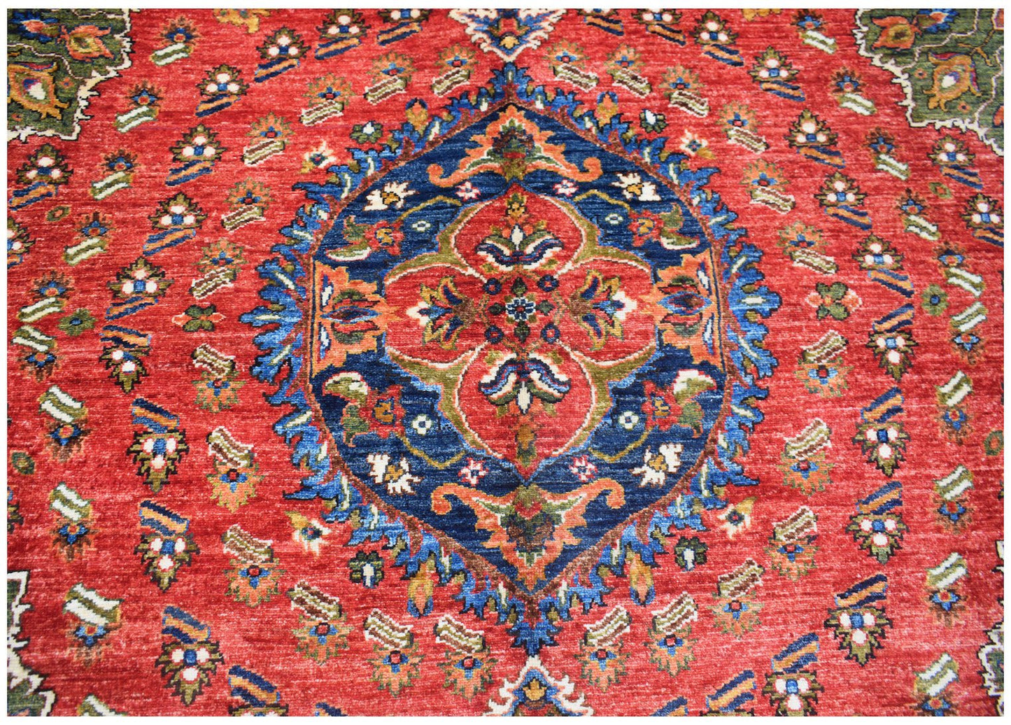A handmade Afghan Chobi rug featuring a central blue medallion on a red field with floral motifs.