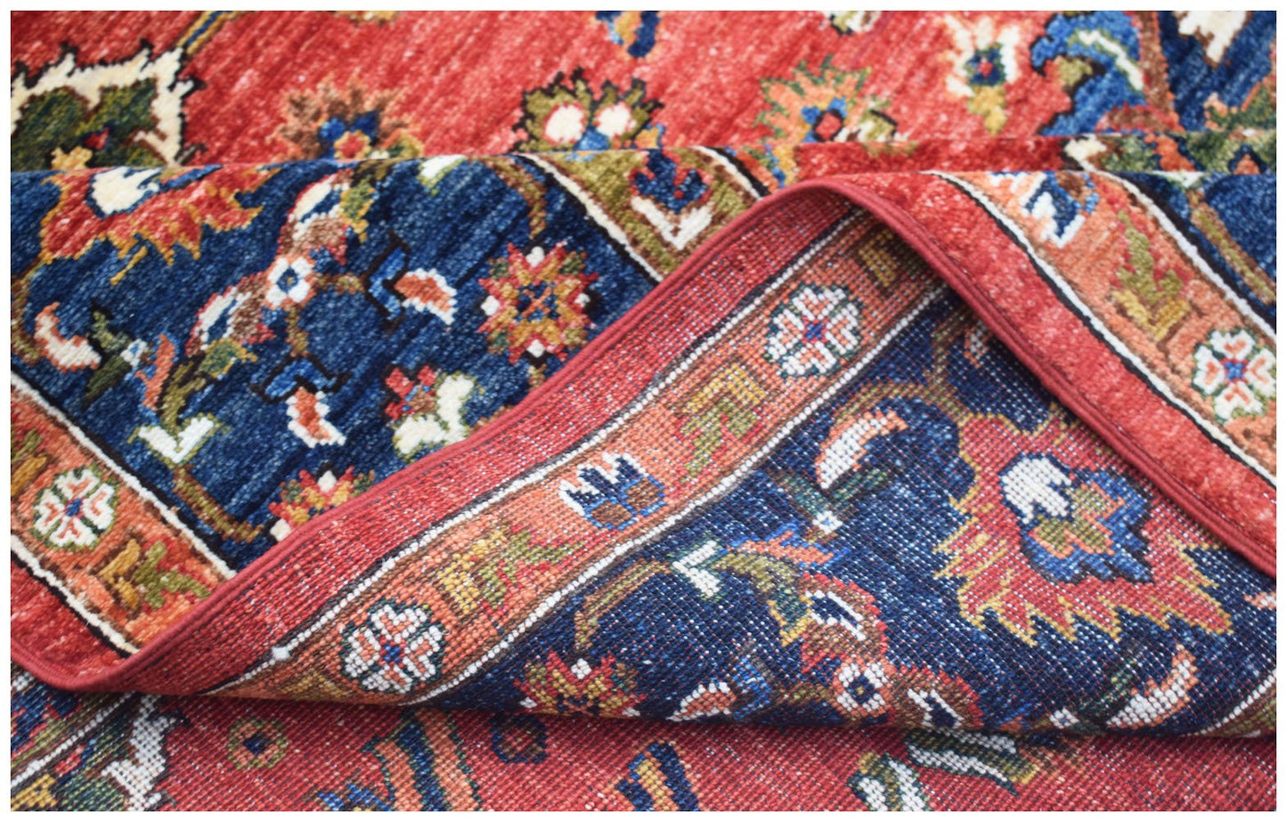 A handwoven Afghan Chobi rug featuring a traditional floral pattern in red, blue, and earthy tones.