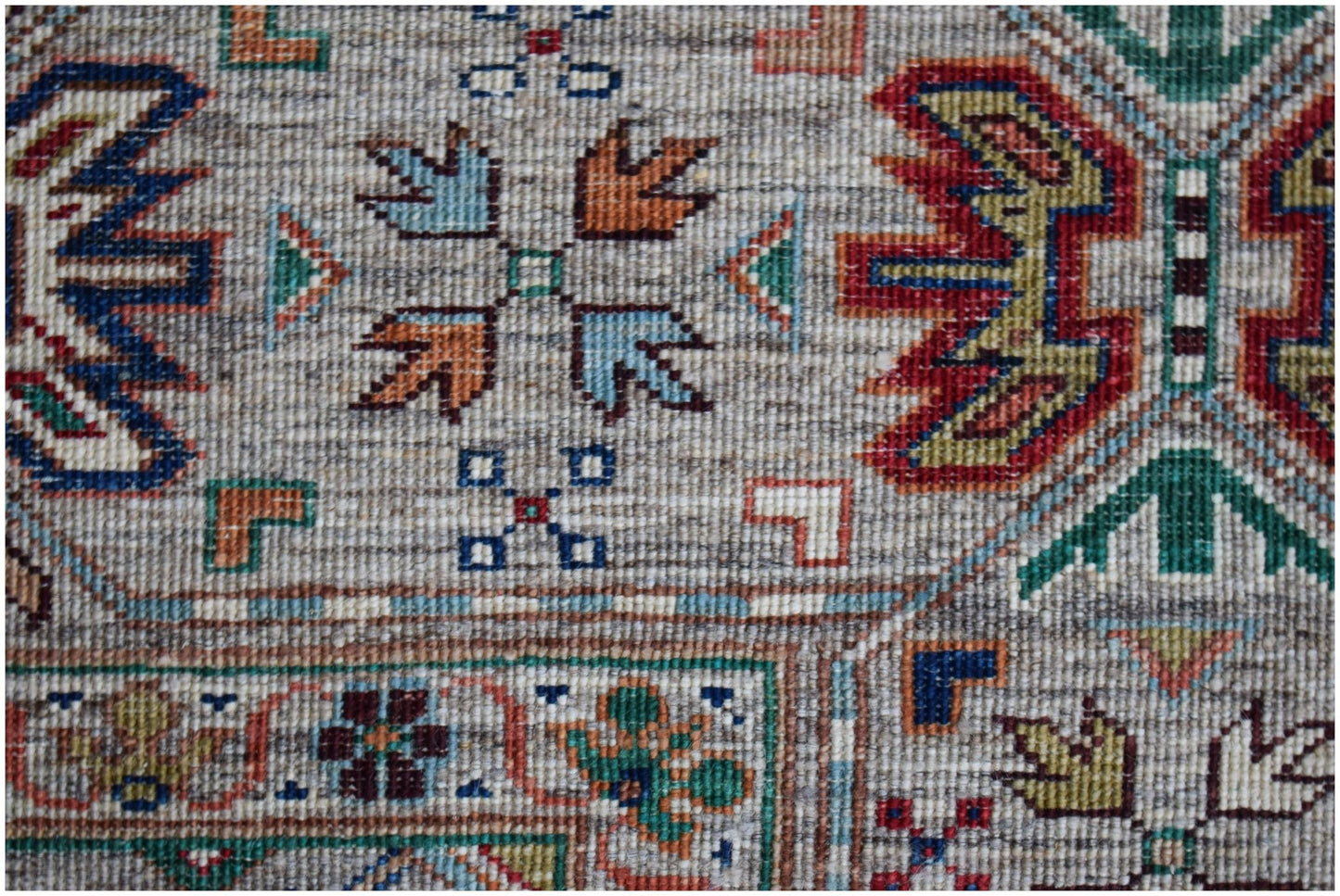 A handwoven Afghan Chobi rug featuring intricate geometric patterns in earthy, multi-colored tones.