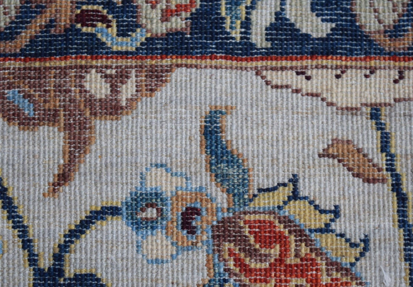 A close-up of a handwoven Afghan Chobi rug featuring intricate floral and hunting scene patterns.