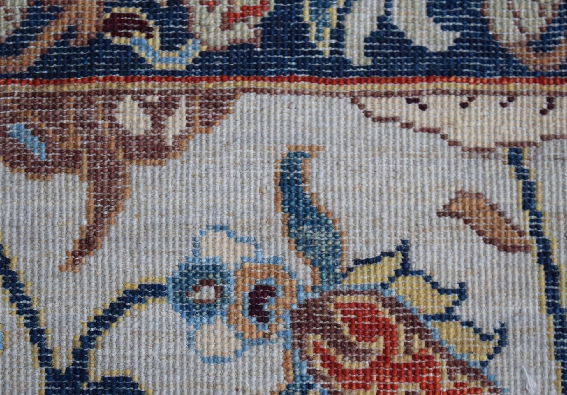 A close-up of a handwoven Afghan Chobi rug featuring intricate floral and hunting scene patterns.
