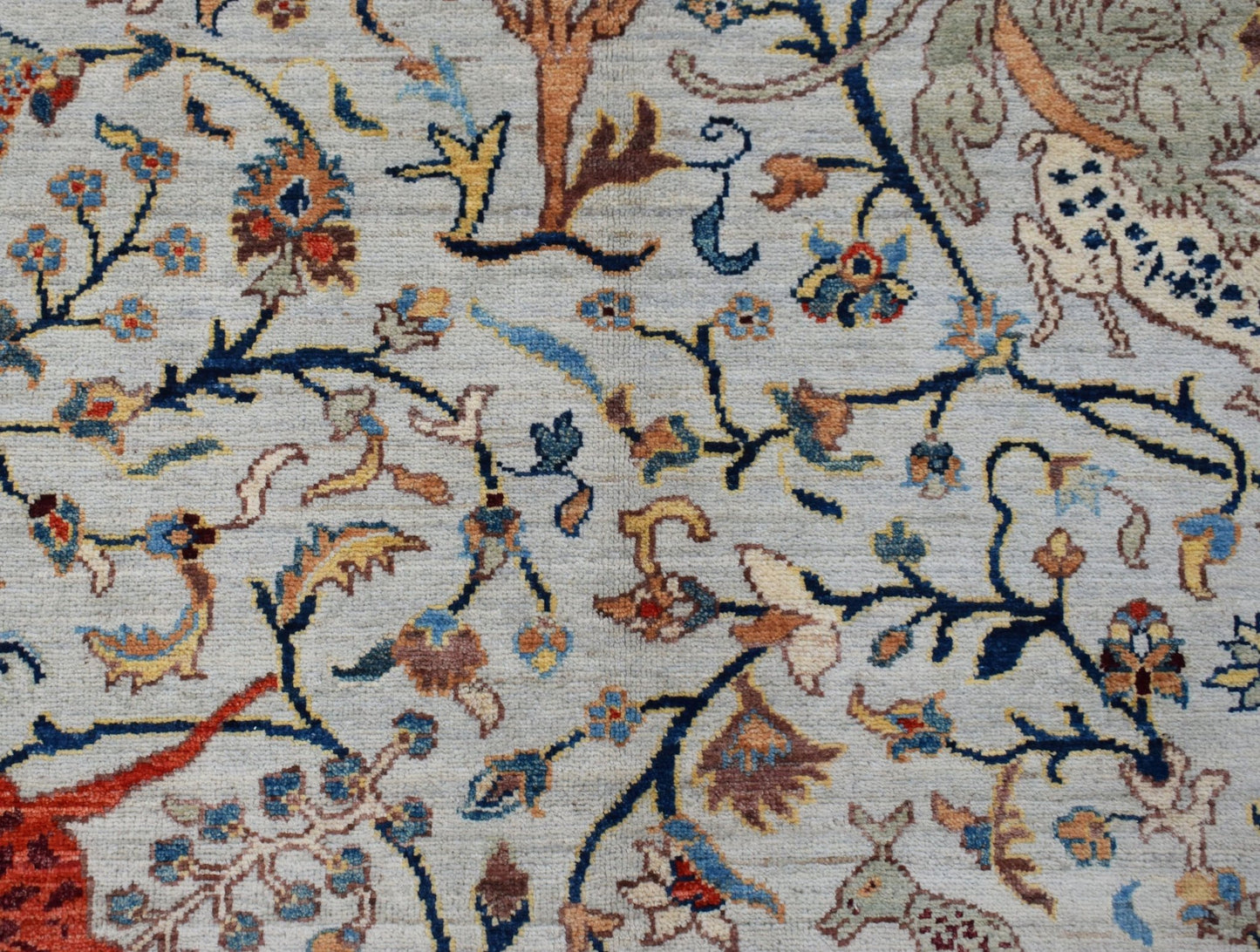 Handwoven Afghan Chobi rug featuring a detailed hunting scene with floral motifs on a light field.