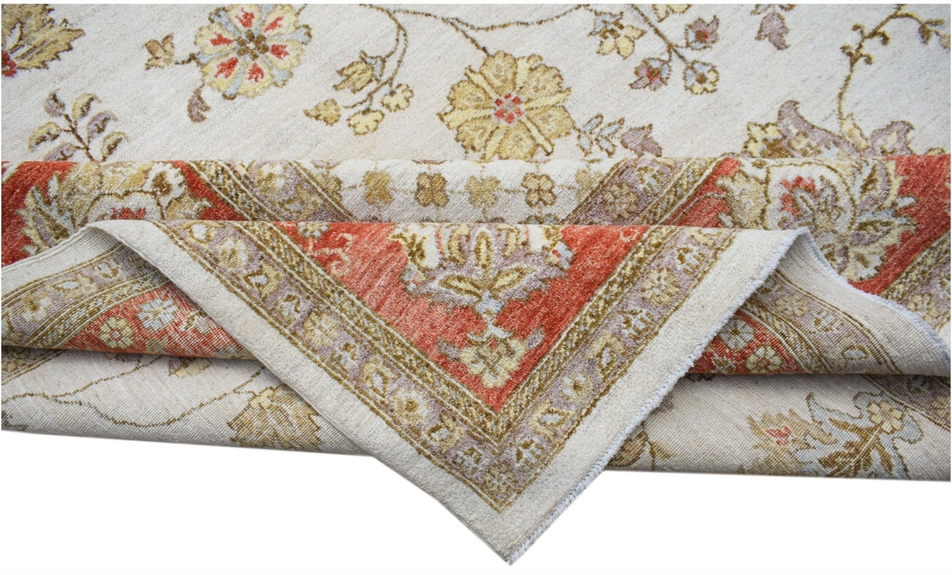 An Afghan Chobi rug with a cream field and floral patterns folded to show its red border.