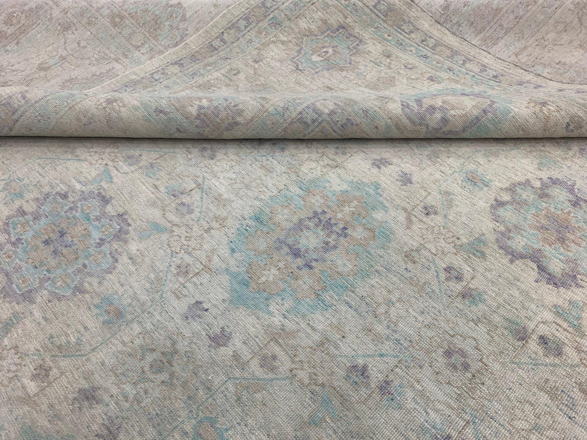 A handmade Afghan Chobi rug featuring a traditional floral pattern in soft blue and beige tones.
