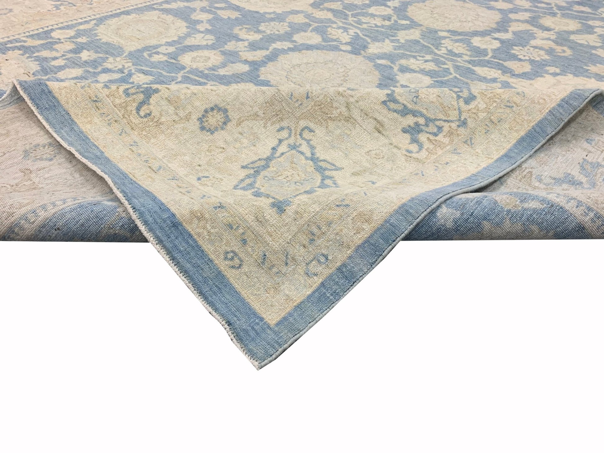 A handmade Afghan Chobi rug featuring a traditional floral pattern in soft blue and beige tones.