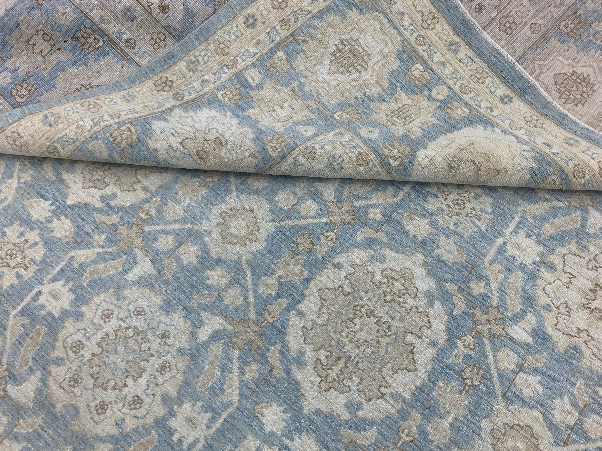 A handmade Afghan Chobi rug featuring a traditional floral pattern in shades of blue and beige.