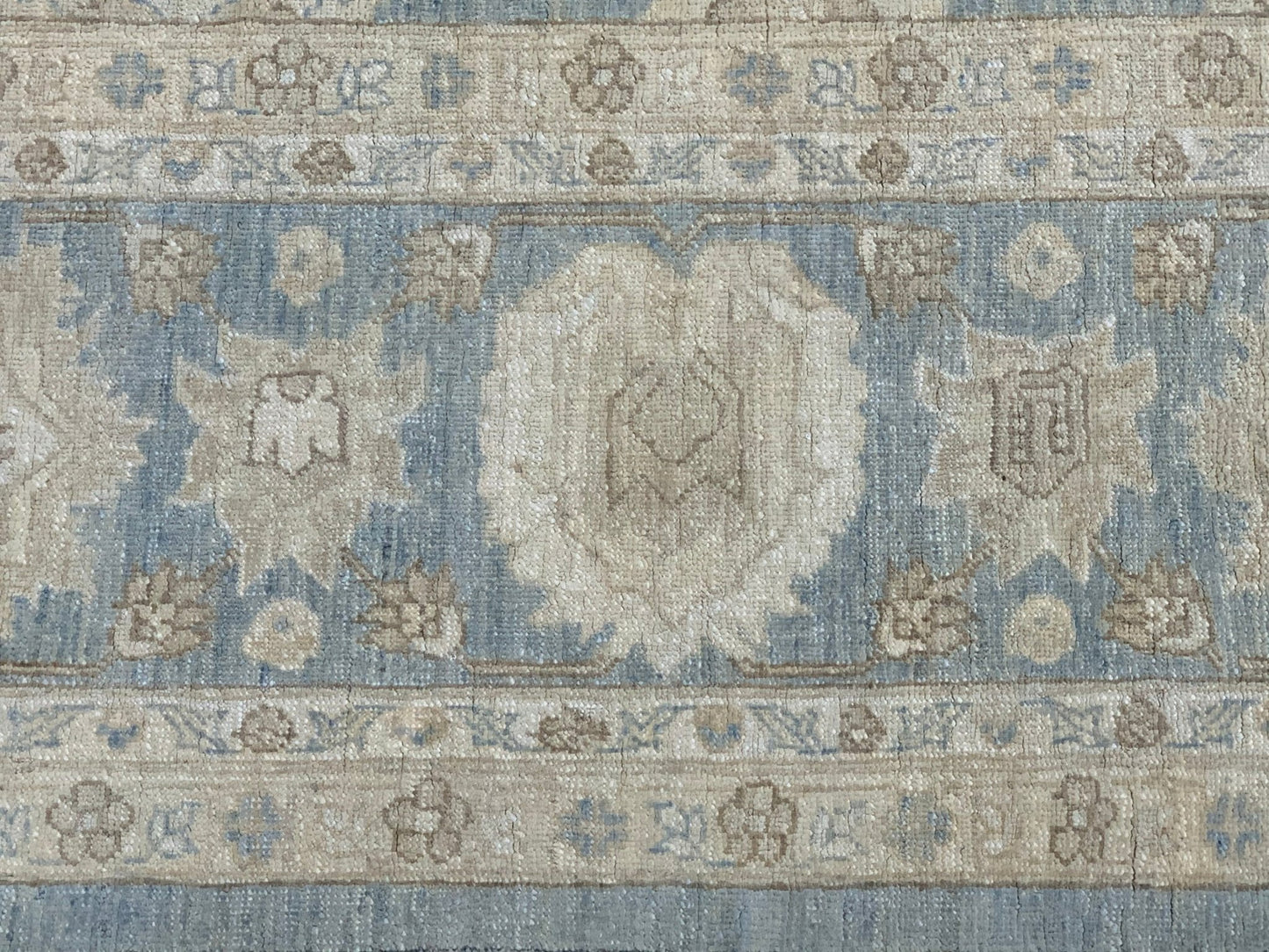 A handmade Afghan Chobi rug featuring a traditional floral pattern in soft blue and beige tones.