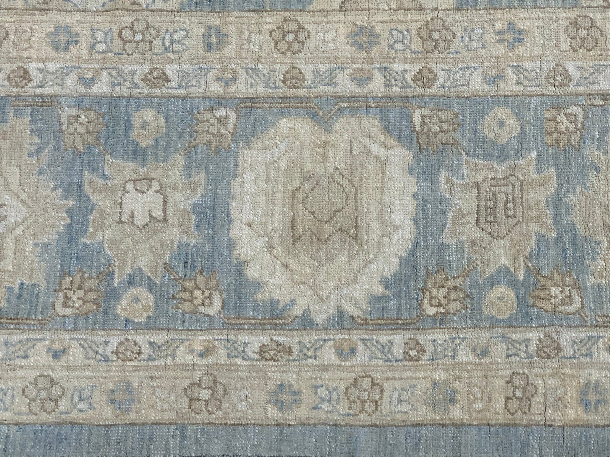 A handmade Afghan Chobi rug featuring a traditional floral pattern in soft blue and beige tones.