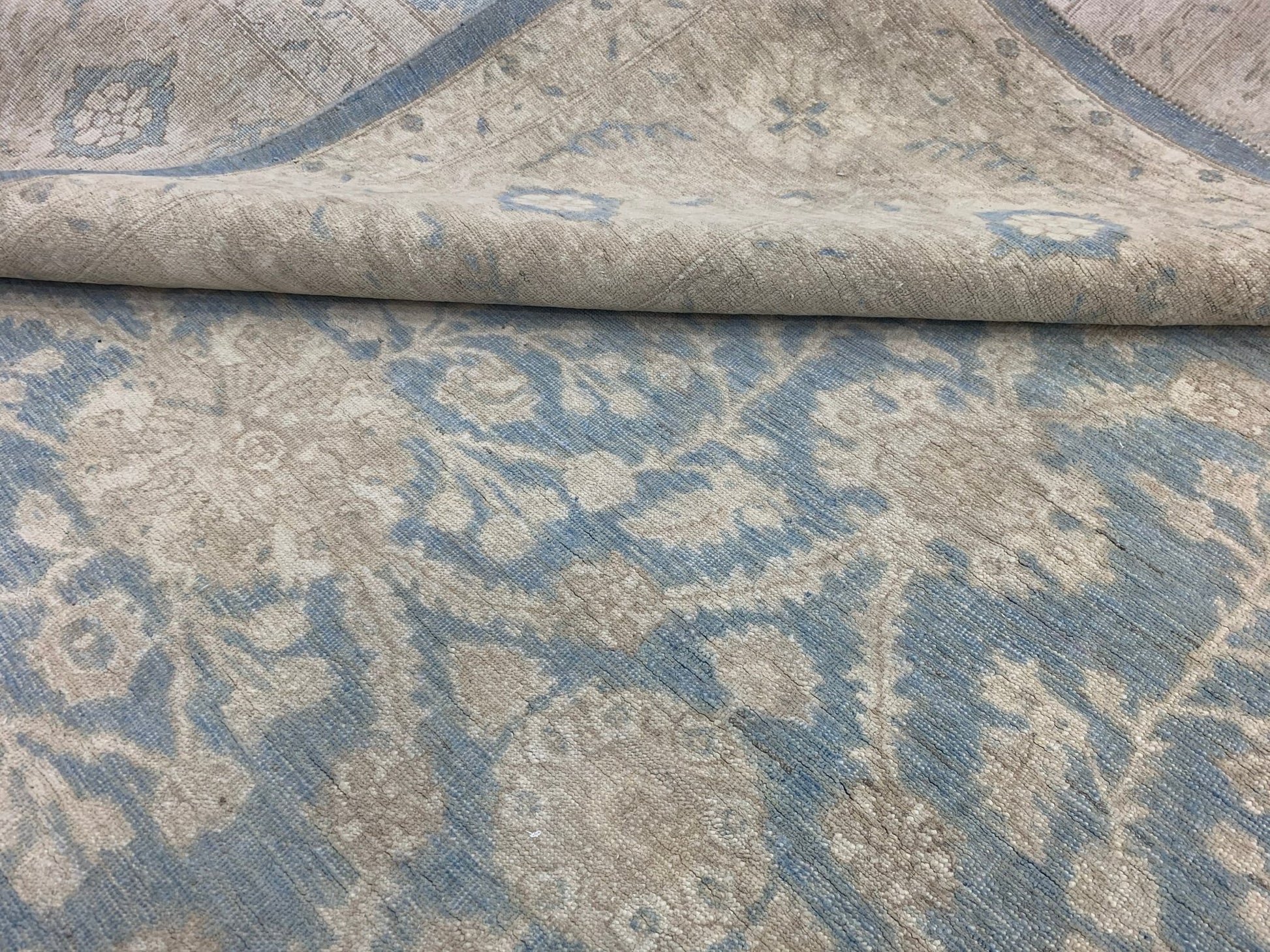A handmade Afghan Chobi rug featuring a traditional floral pattern in soft blue and beige tones.