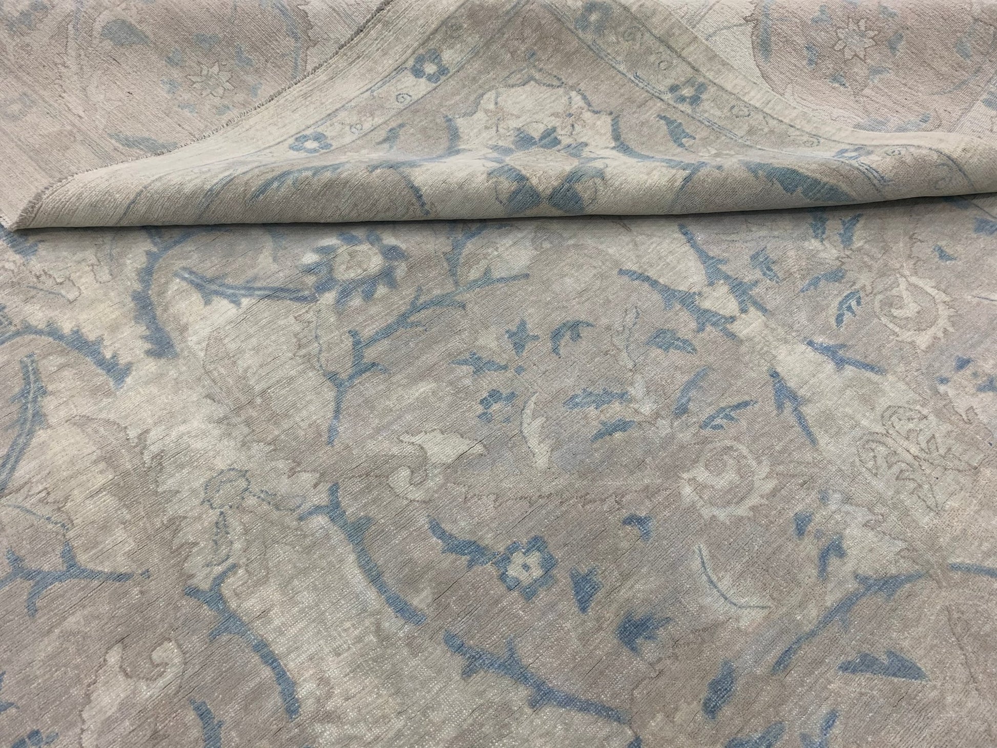 A handmade Afghan Balkh rug featuring a traditional floral pattern in soft blue and beige tones.