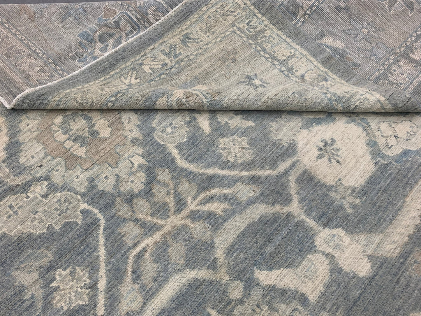 A handmade Afghan Chobi rug featuring a traditional floral pattern in shades of blue and cream.