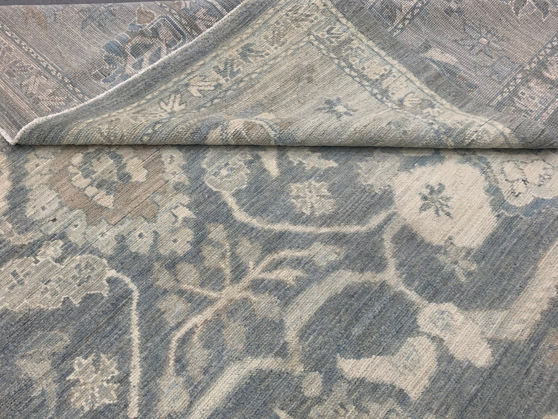 A handmade Afghan Chobi rug featuring a traditional floral pattern in shades of blue and cream.