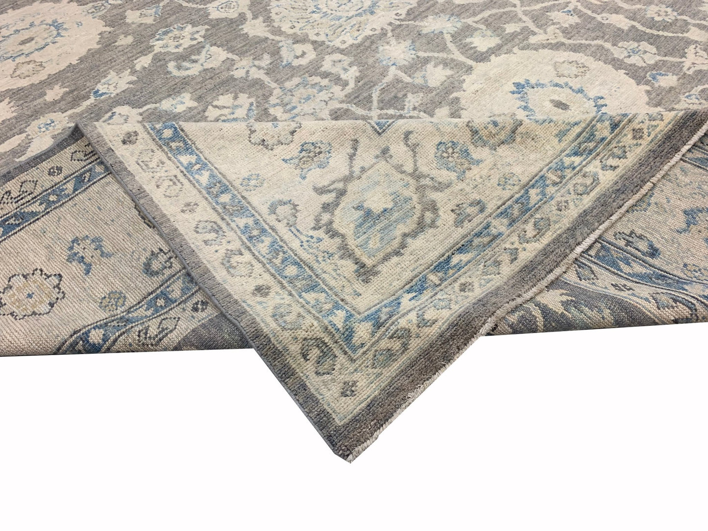 A handmade Afghan Chobi rug featuring a traditional floral pattern in shades of grey and blue.