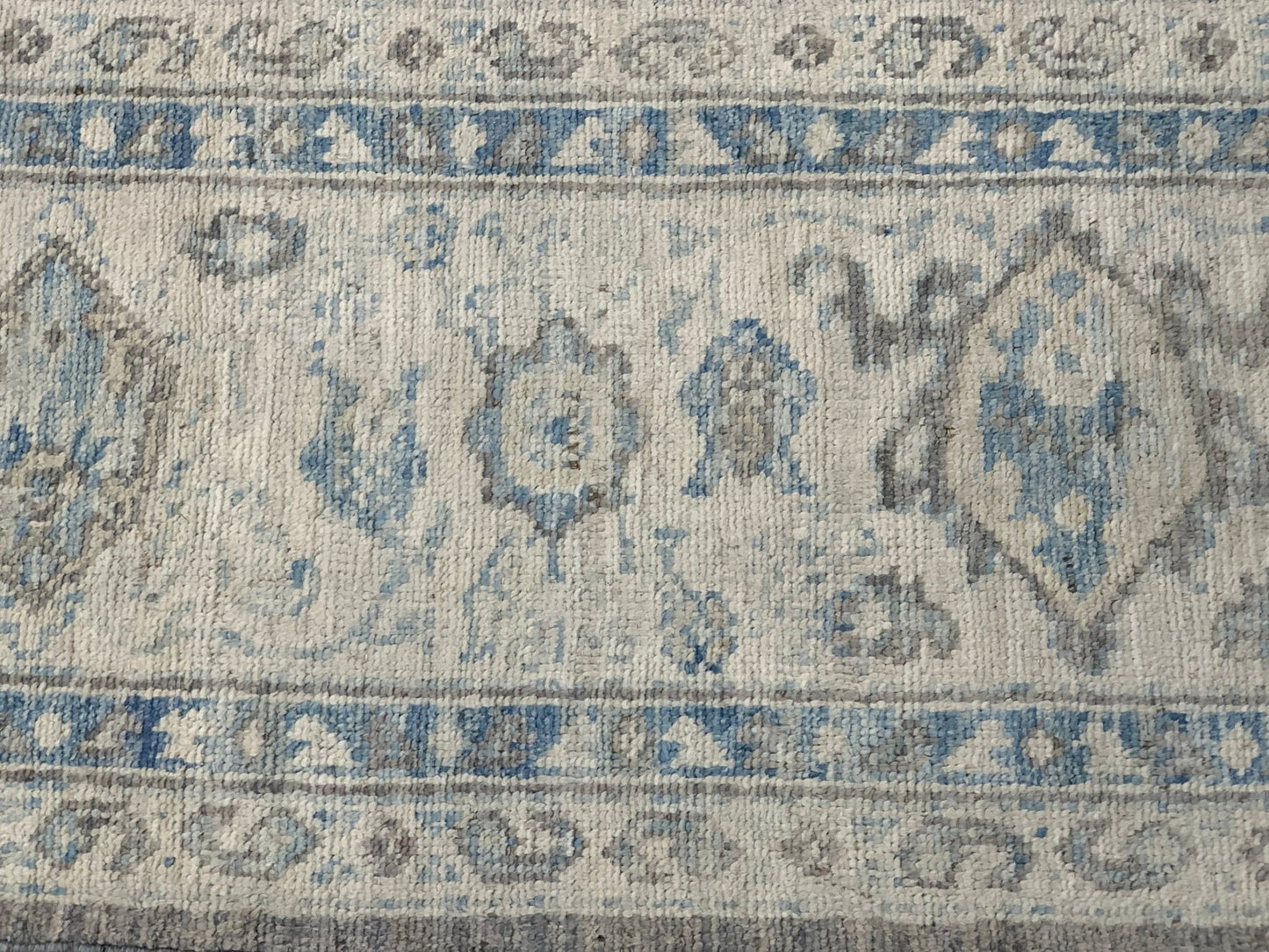 An Afghan Chobi rug featuring a traditional blue and grey floral pattern on a cream background.