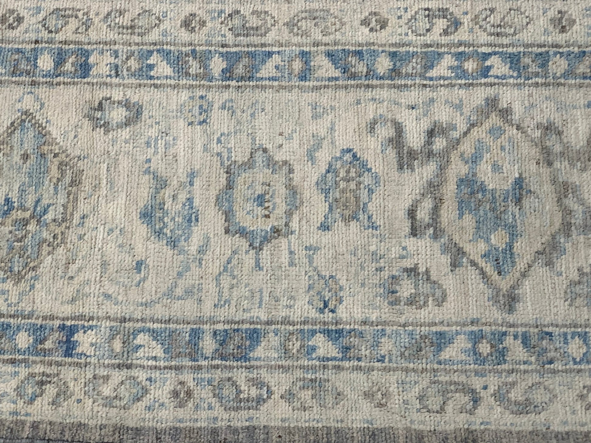 An Afghan Chobi rug featuring a traditional blue and grey floral pattern on a cream background.