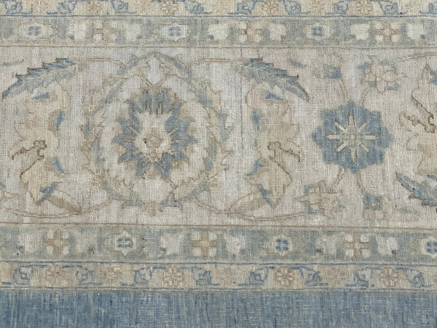 A handmade Afghan Balkh rug featuring a traditional floral pattern in muted blue and beige tones.