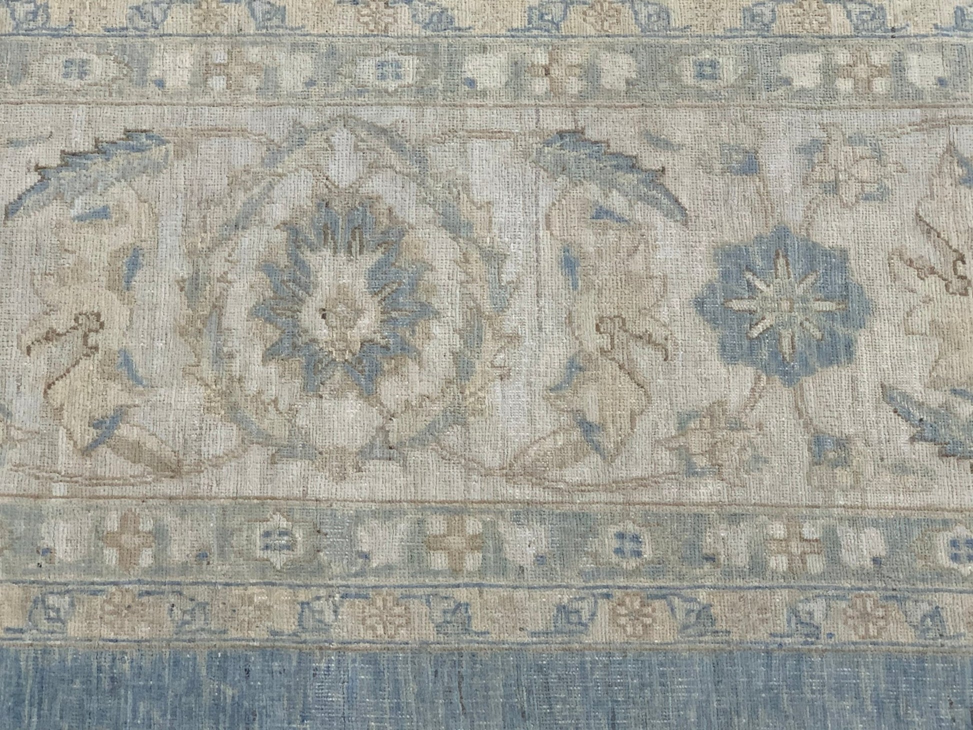 A handmade Afghan Balkh rug featuring a traditional floral pattern in muted blue and beige tones.