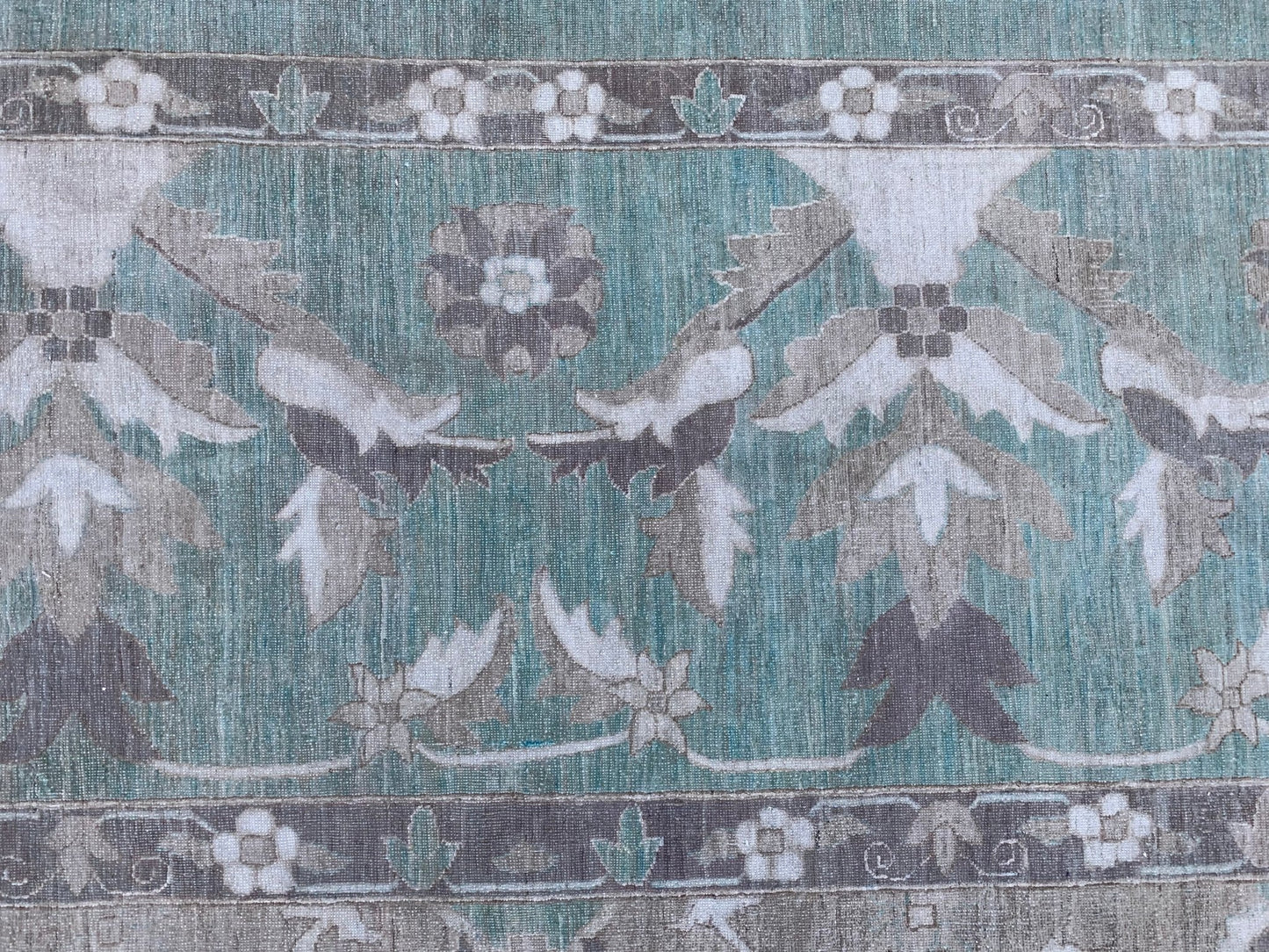 A handmade Afghan Chobi rug featuring a teal field with intricate floral and botanical patterns.
