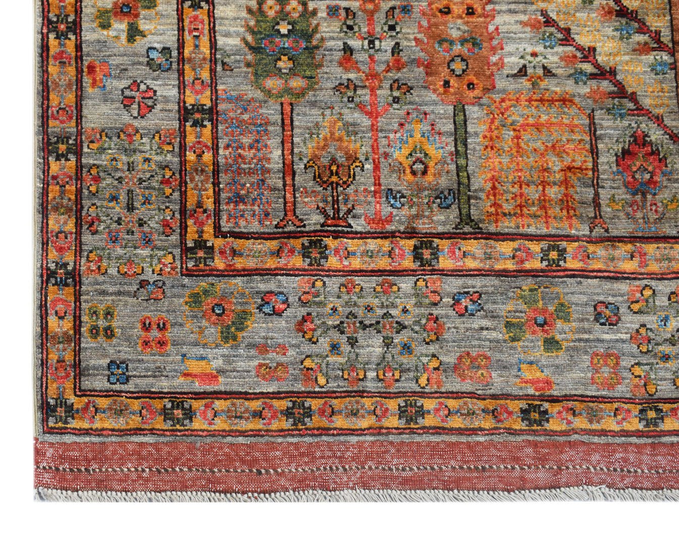 Handwoven Afghan Chobi rug featuring a Tree of Life pattern in earthy tones on a grey background.
