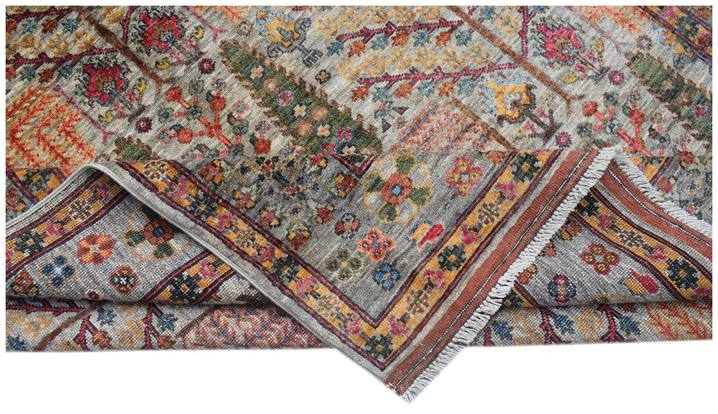 A handwoven Afghan Chobi rug featuring a colorful Tree of Life pattern on a grey background.